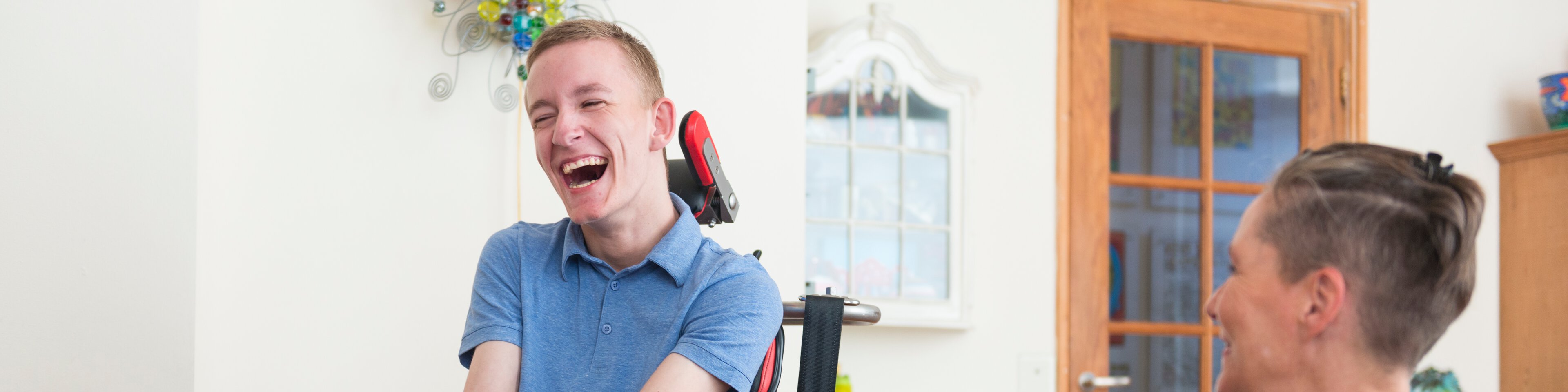 Eine Betreuerin und ein Mann im Rollstuhl lachen gemeinsam | © KIVILCIM - funky data - Getty Images